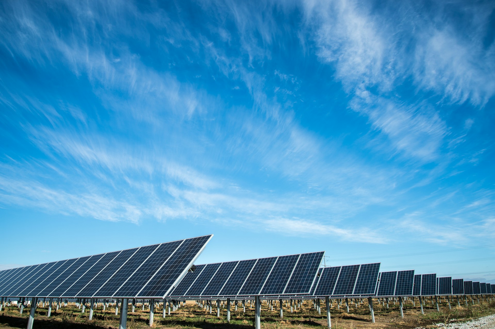 Rows of solar panels under an open blue sky.