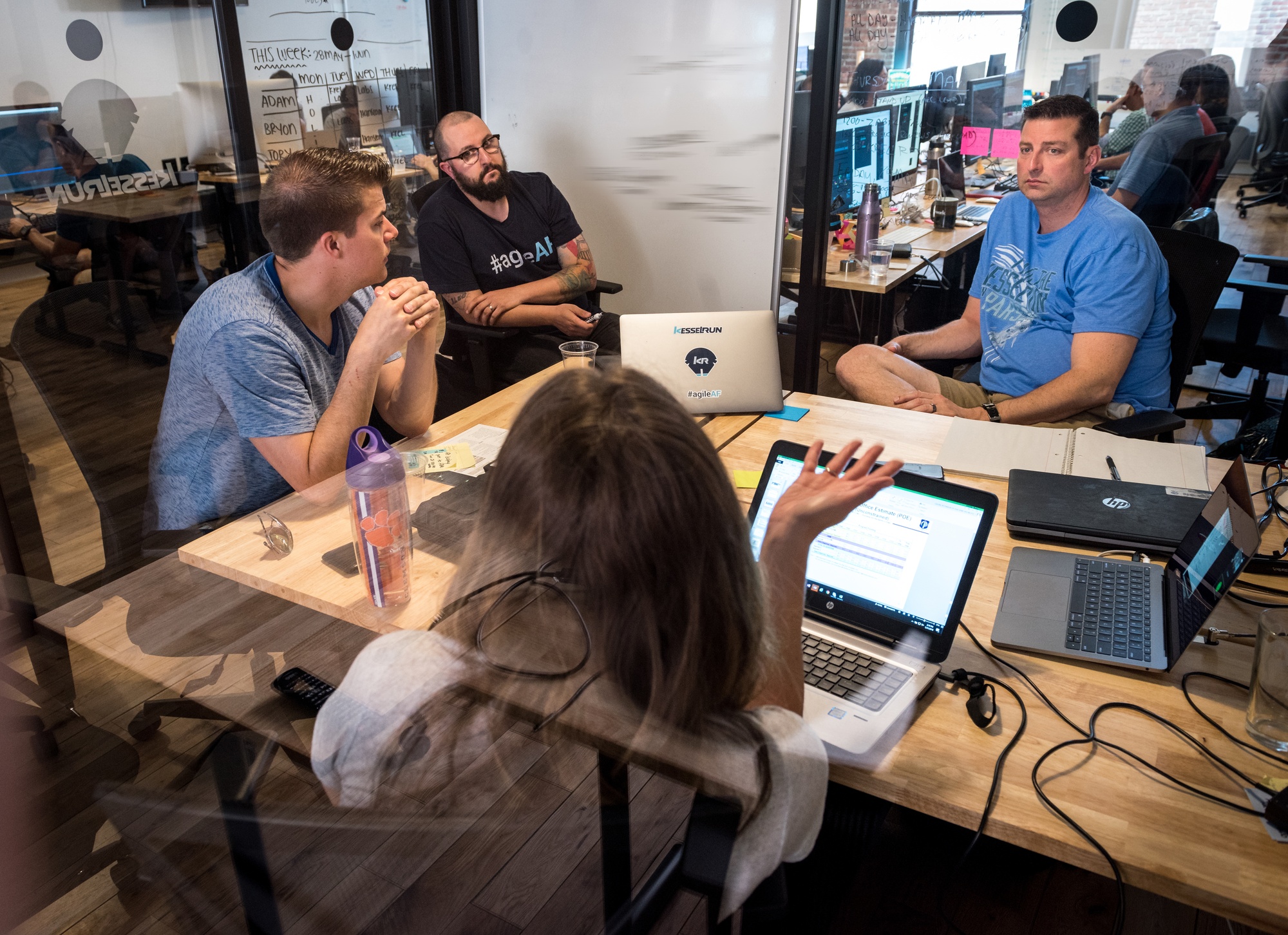 Civilian and Air Force software leaders discuss projects around a table with open laptops.