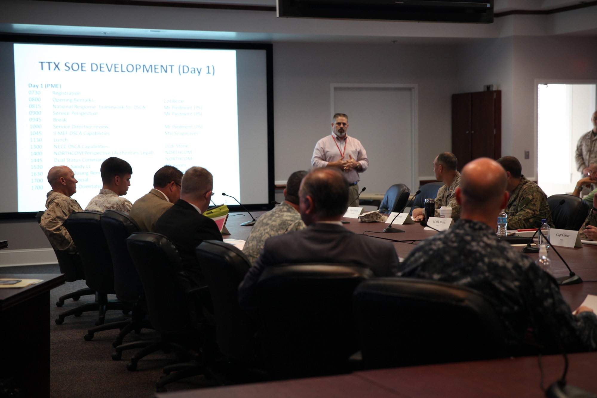 Civilian and military planners work around a conference table during a disaster-response planning exercise.